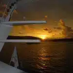 Amanecer dorado visto desde un crucero navegando entre islas volcánicas en Galápagos