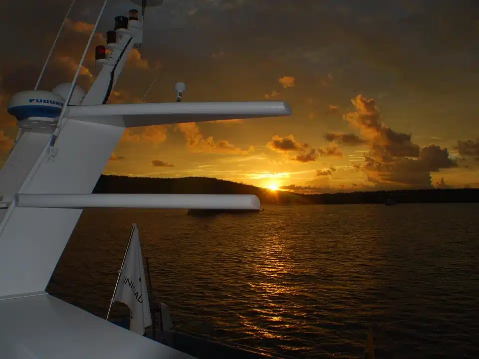 Amanecer dorado visto desde un crucero navegando entre islas volcánicas en Galápagos